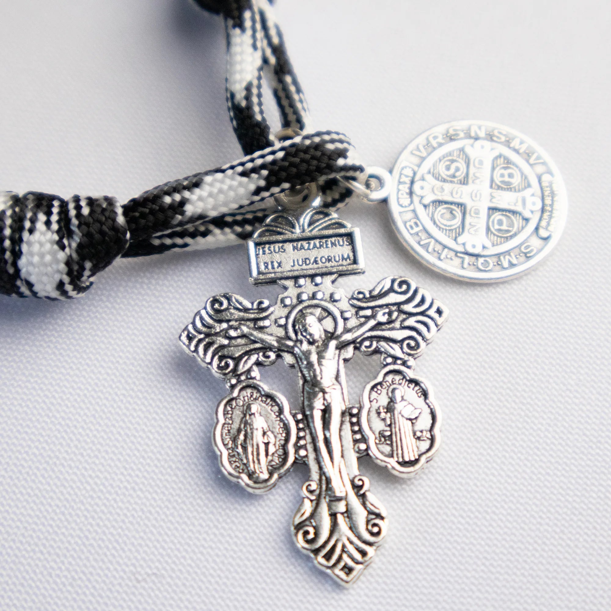 Detalle del Denario Católico Crux Invicta con cordón blanco y negro y cuentas metálicas