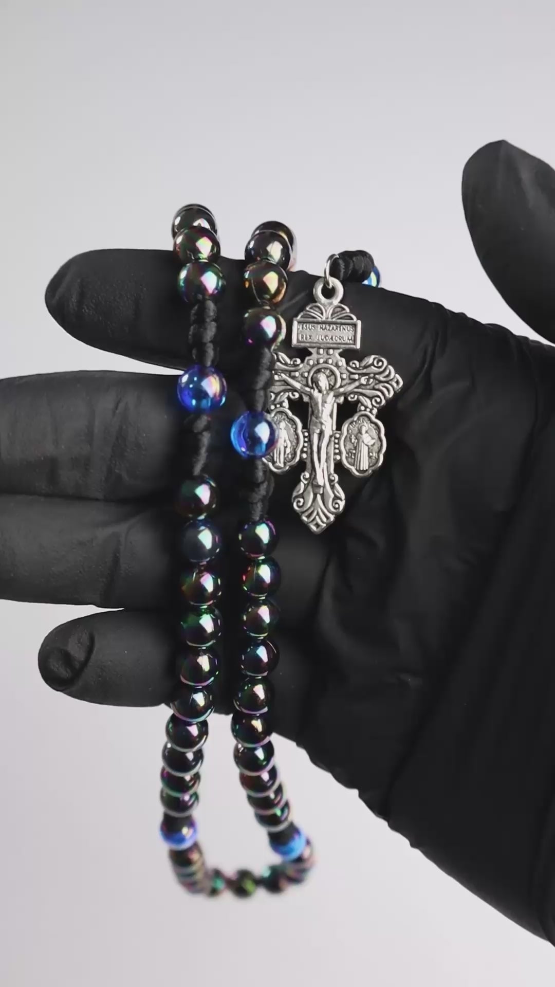 Rosario católico Mysterium Lucis sostenido en la mano con cuentas tornasoladas y cruz plateada