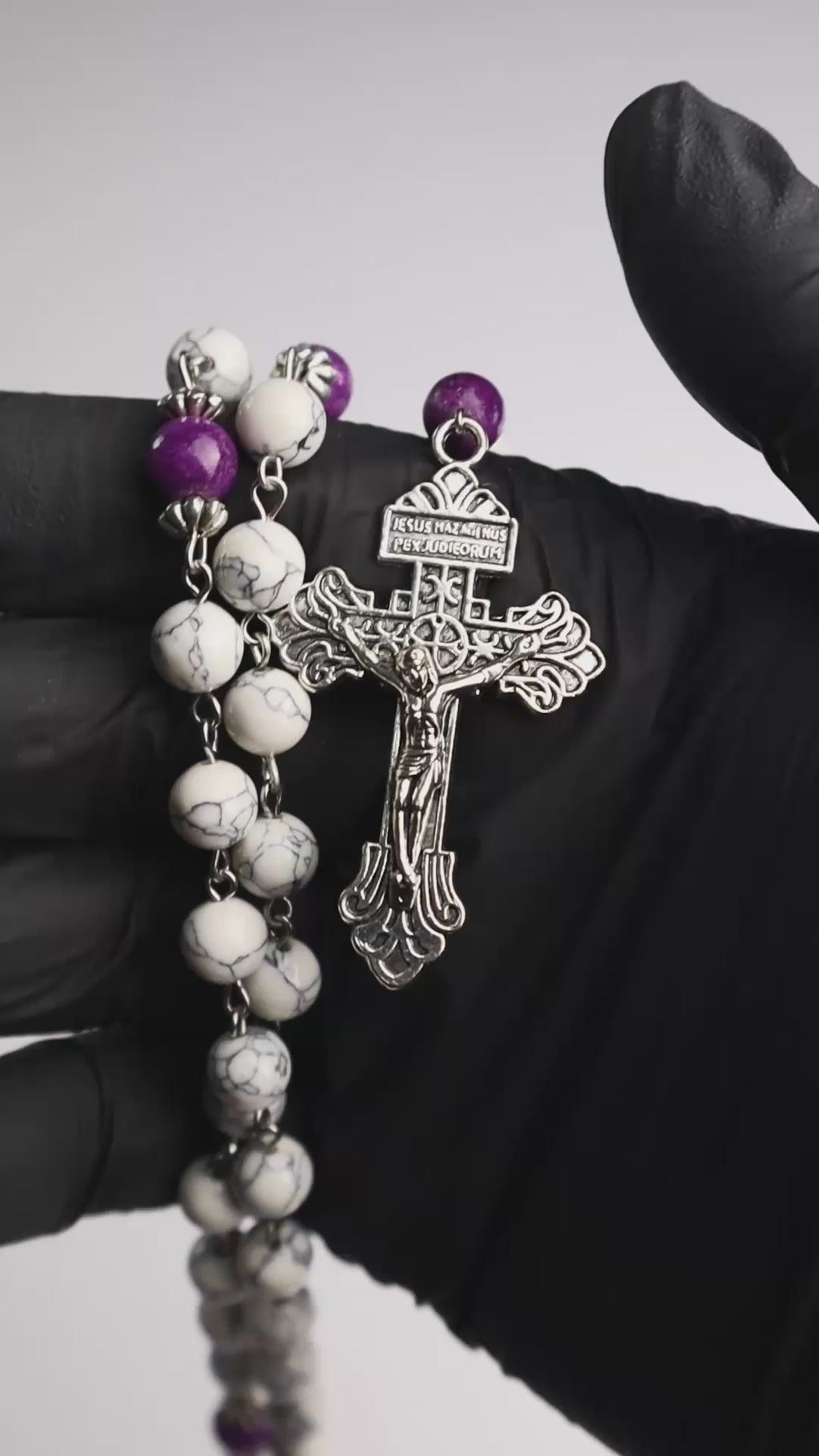 Rosario católico Mater Dolorosa sostenido en la mano con piedras naturales y cruz metálica