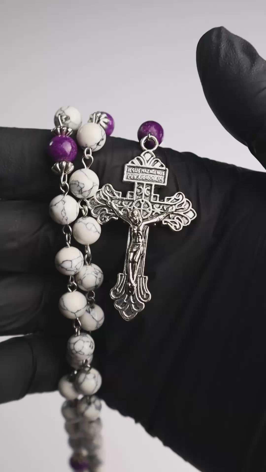 Rosario católico Mater Dolorosa sostenido en la mano con piedras naturales y cruz metálica